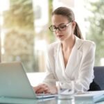 Confident businesswoman using a laptop at her desk, focused on her work.